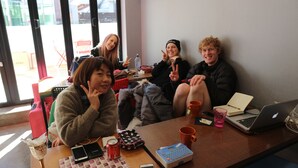A group of people sitting at a table with a laptop, a mobile phone, a calculator, and a can of Coca-Cola. - Zzzip Guest House - Hostel (Seoul)