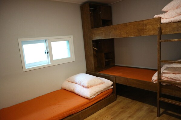A bunk bed room with a window, wooden shelves, and orange bedding. - Zzzip Guest House - Hostel (Seoul)