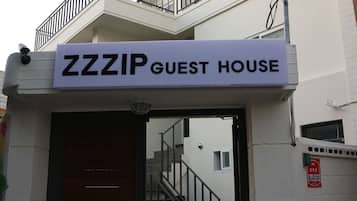 A building entrance with a sign reading "ZZZIP GUEST HOUSE".