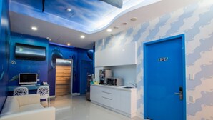 A modern room with a blue accent wall, a microwave, a sink, and a door marked with the number 108. - Morwing Hotel - Ocean (New Taipei City)
