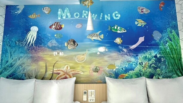 A bedroom with a mural of an underwater scene, a ceiling light, and a bed with white bedding. - Morwing Hotel - Ocean (New Taipei City)