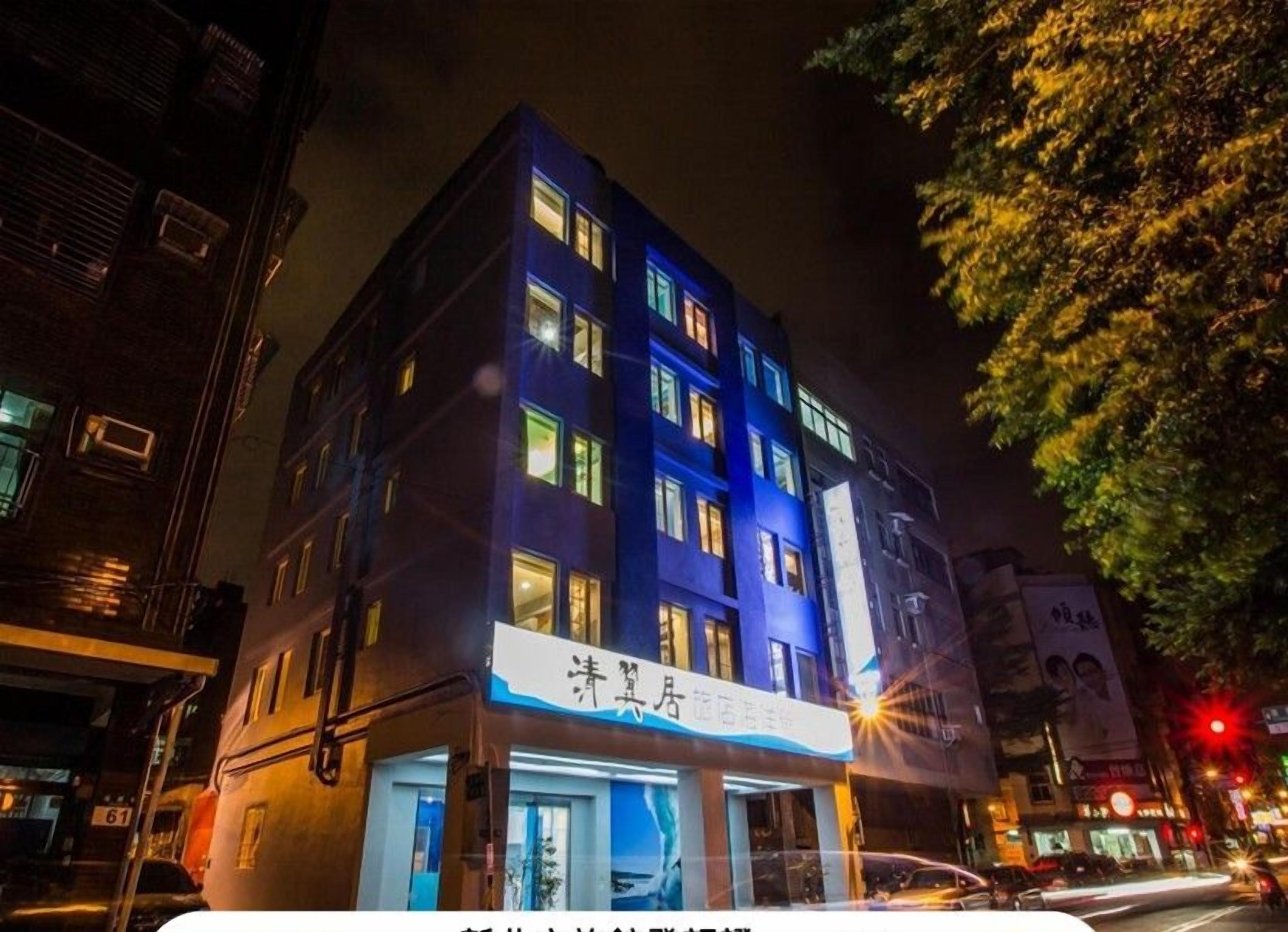 A multi-story hotel with illuminated signage and windows, located on a city street at night.