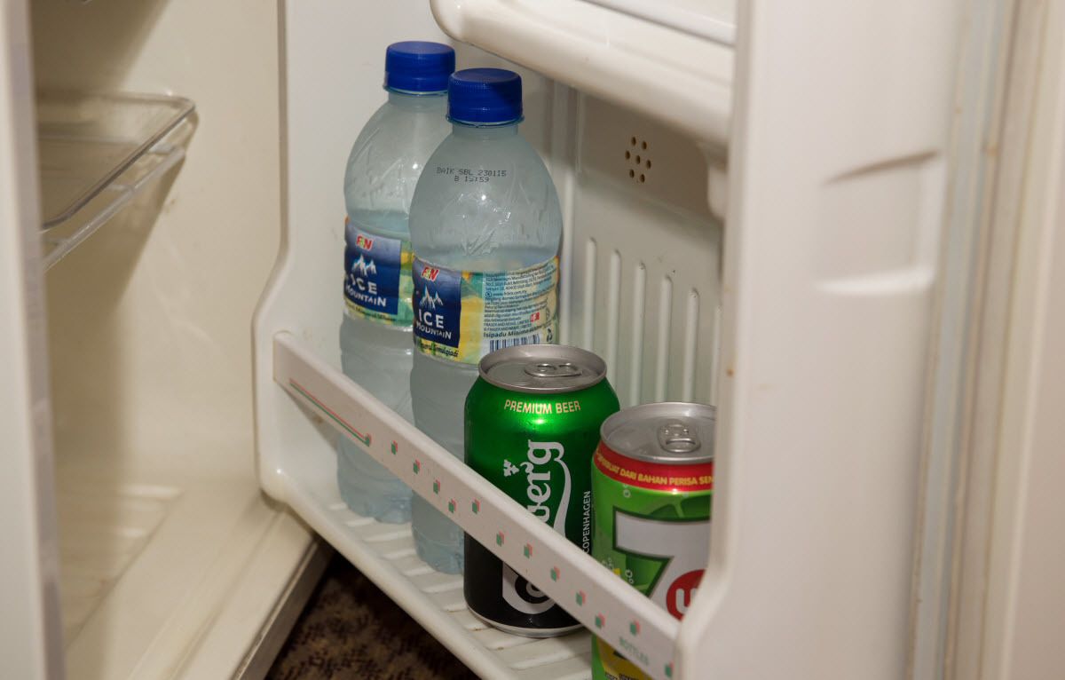 Un refrigerador con dos botellas de agua y dos latas de cerveza.