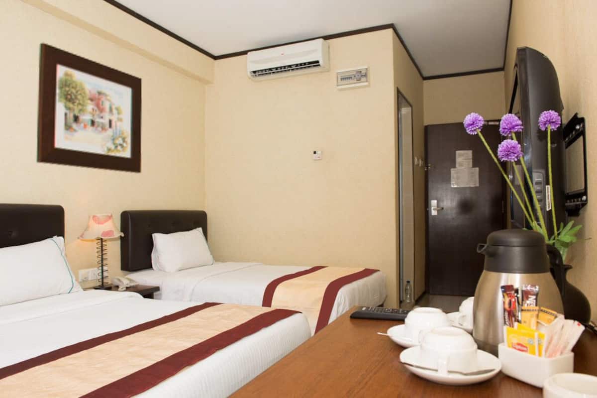 Una camera d'albergo con due letti, una televisione, una macchina del caffè e un quadro appeso al muro.