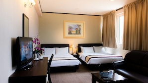 A hotel room with two beds, a TV, a desk with a laptop, a coffee cup, and a painting on the wall. - Hotel Vistaria (Johor Bahru)