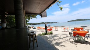 Un restaurant situé en bord de mer, avec une terrasse, une vue sur l’océan et un panneau indiquant qu’il s’agit d’un restaurant de fruits de mer.