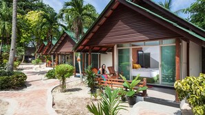 Une rangée de cabanes en bois dotées de grandes fenêtres, entourées d’une végétation tropicale.