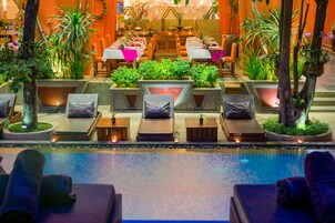 Una piscina al aire libre, sombrillas, sillones reclinables de piscina