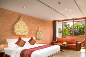 Habitación de hotel moderna con una cama grande, un sofá y vistas a zonas verdes por la ventana.