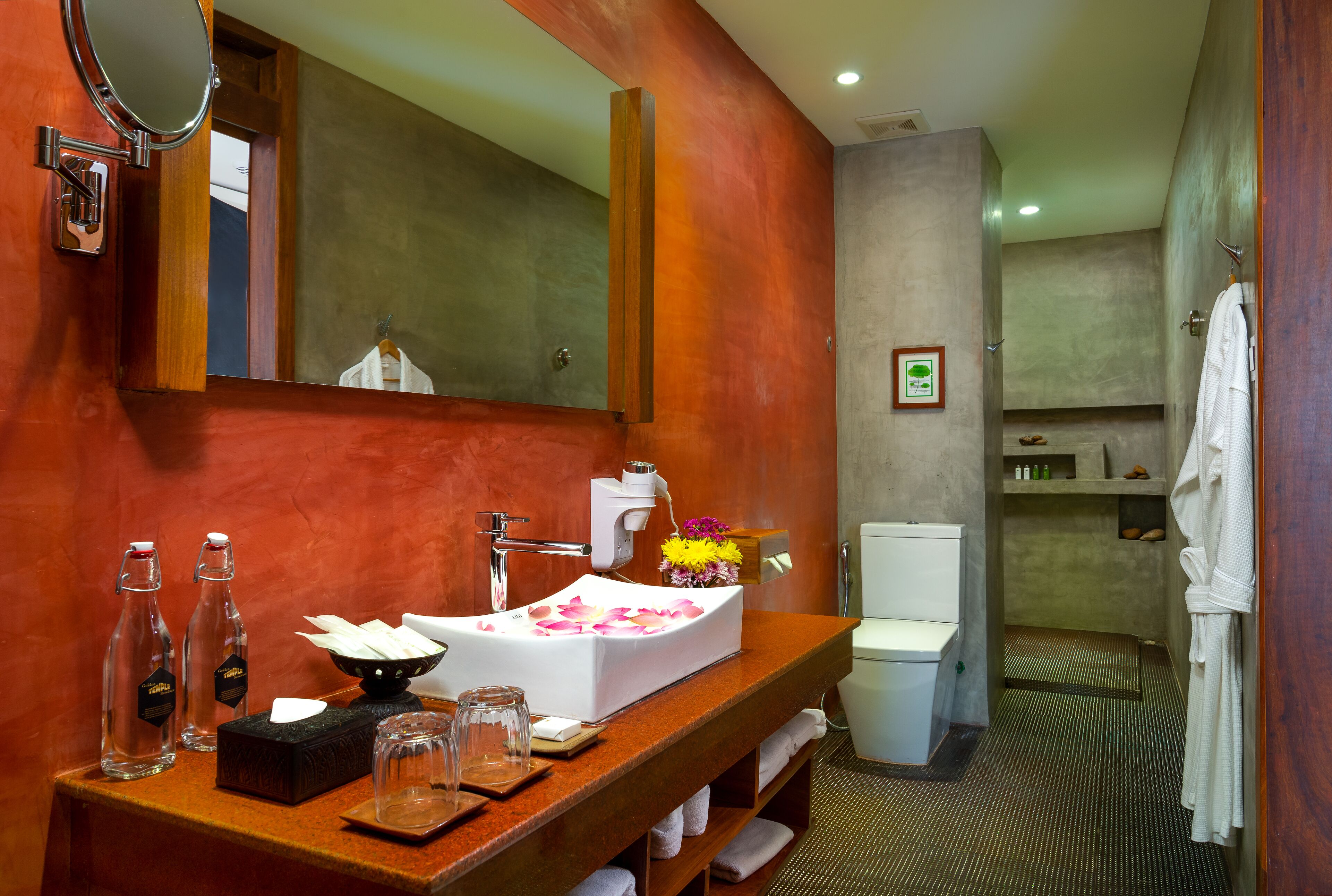 A modern bathroom with a wooden vanity, a large mirror, a white sink, and a shower area.