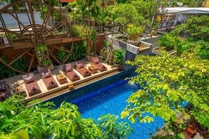 A pool area with a water wheel, lounge chairs, and lush greenery. - Golden Temple Residence (Siem Reap)