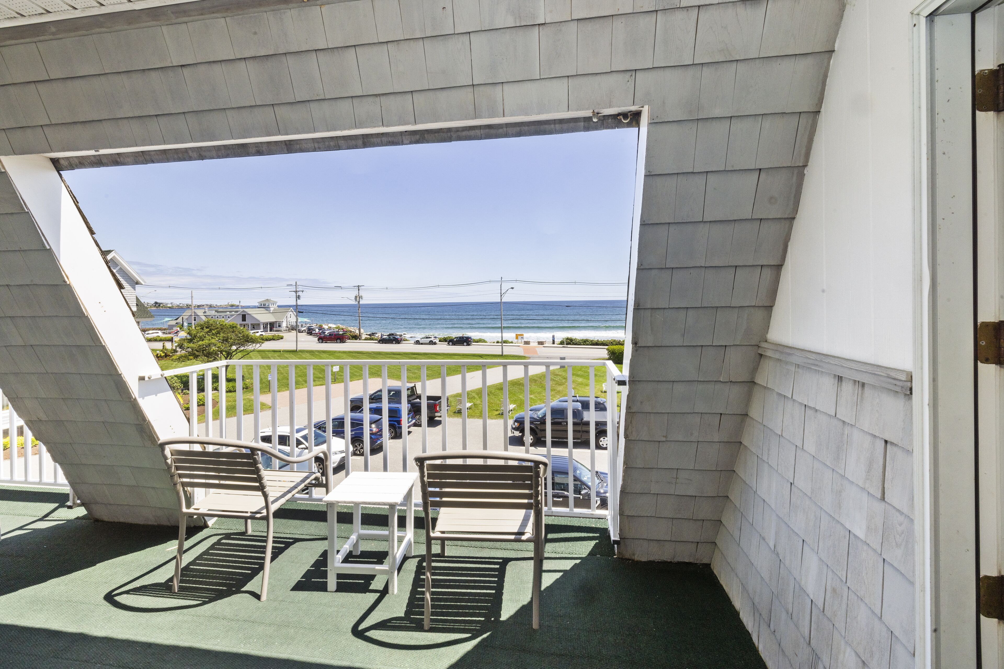 En balkon med udsigt over havet, et bord og to stole.