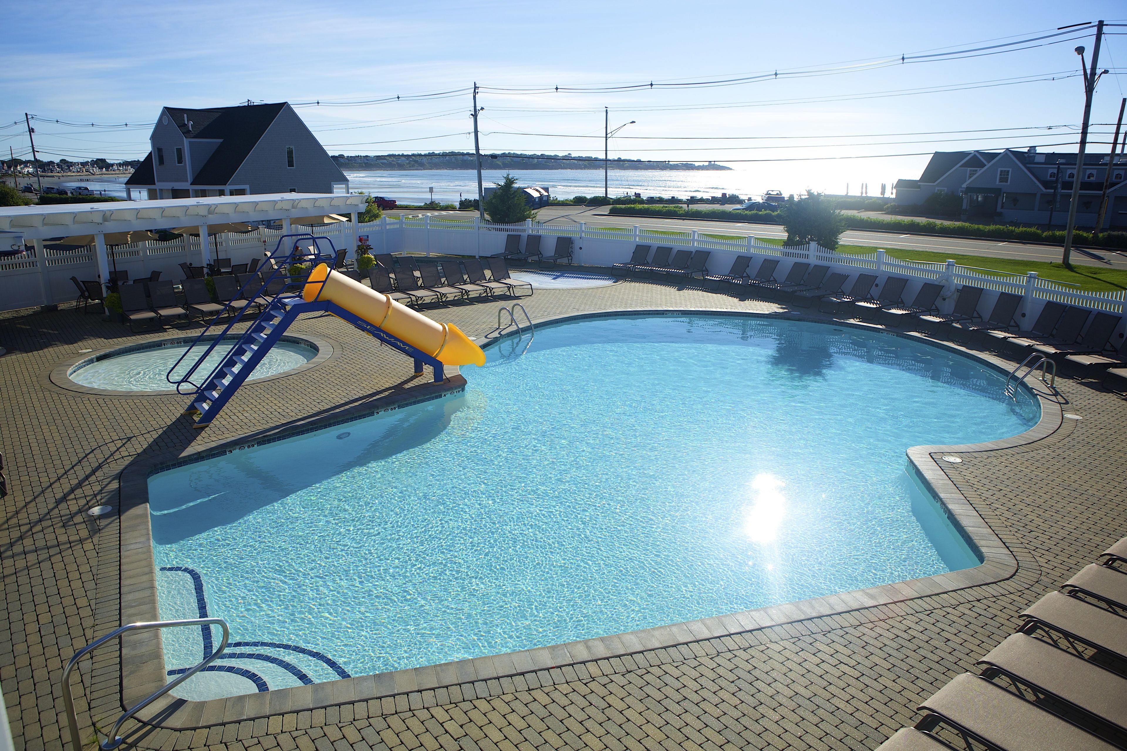 A swimming pool with a slide, lounge chairs, and a view of the sea.