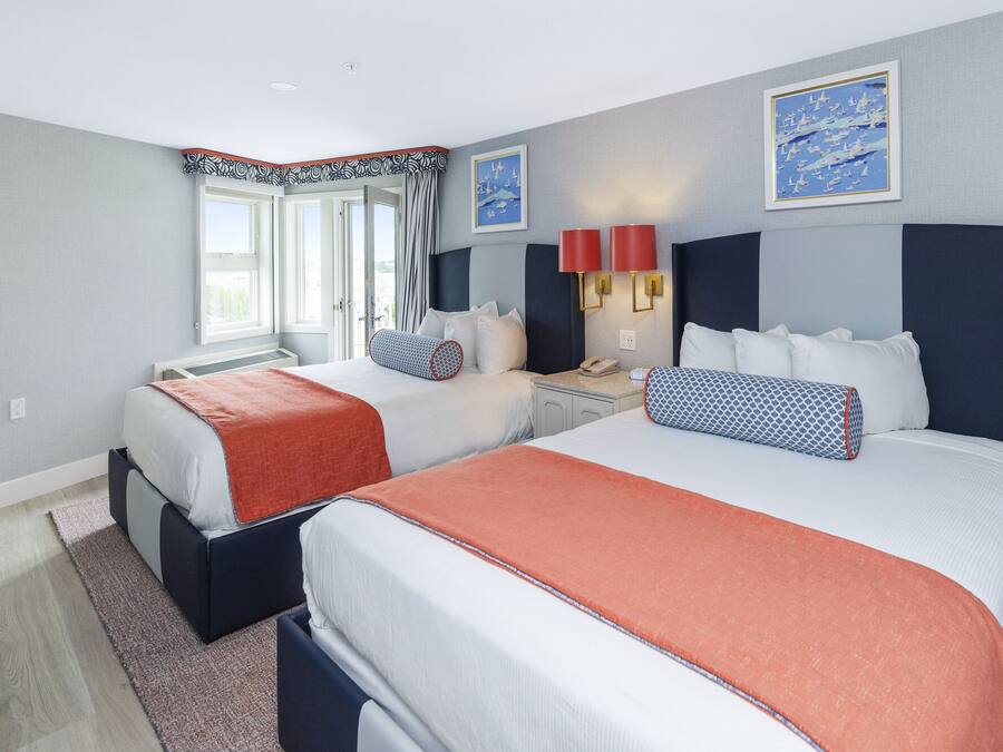 Habitación de hotel con dos camas, una mesita de noche y una ventana con cortinas.