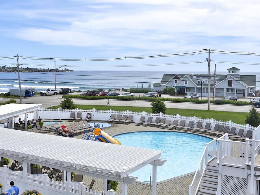 A pool area with a view of the ocean, lounge chairs, and a water slide.