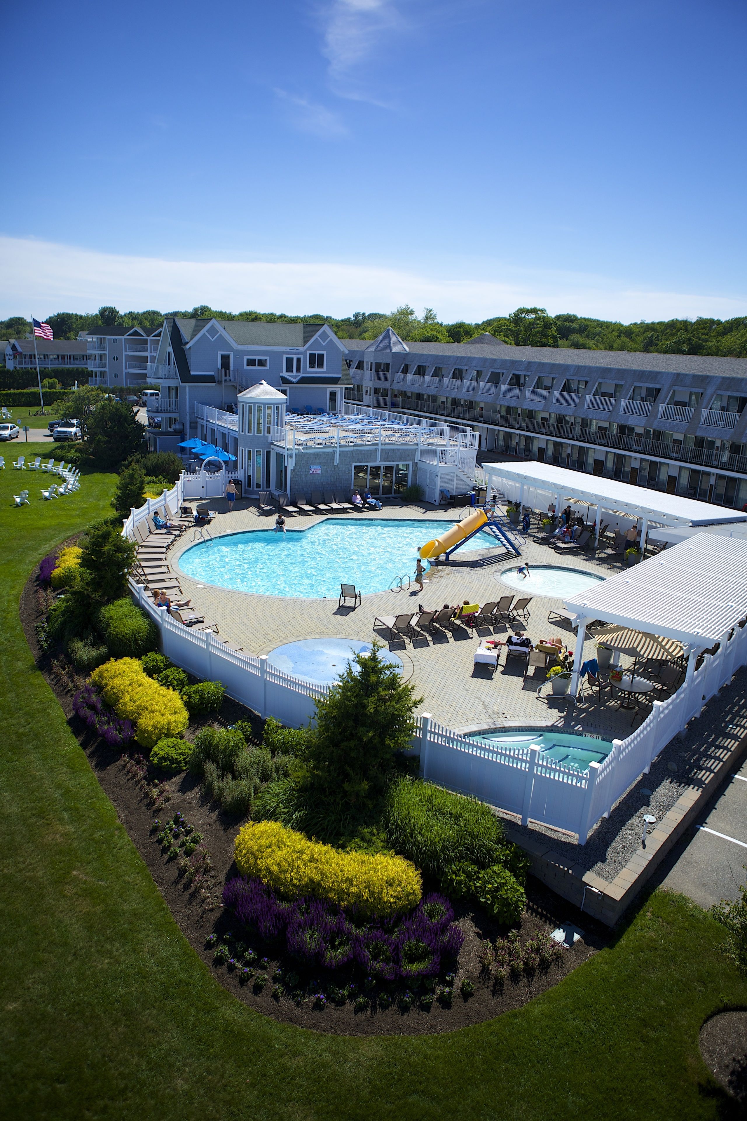 A hotel with a large outdoor pool, lounge areas, and a landscaped garden.