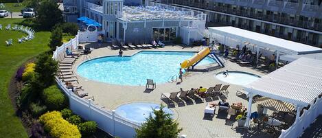 A hotel with a large outdoor pool, lounge areas, and a landscaped garden.