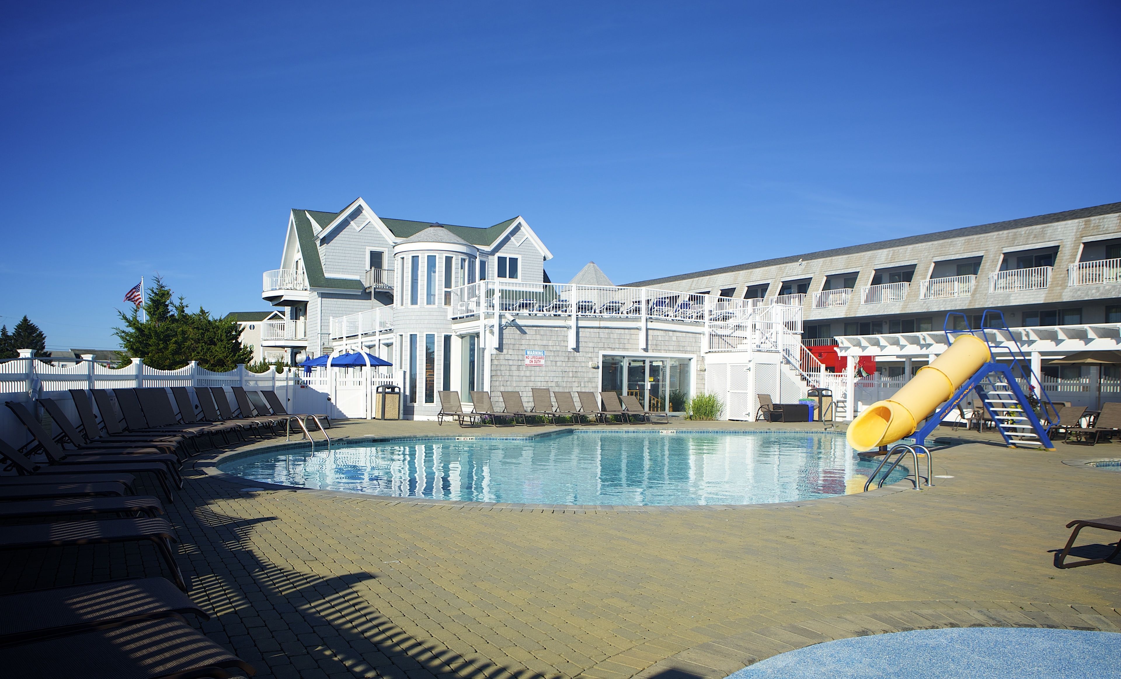 Un espace piscine avec des chaises longues et un toboggan.