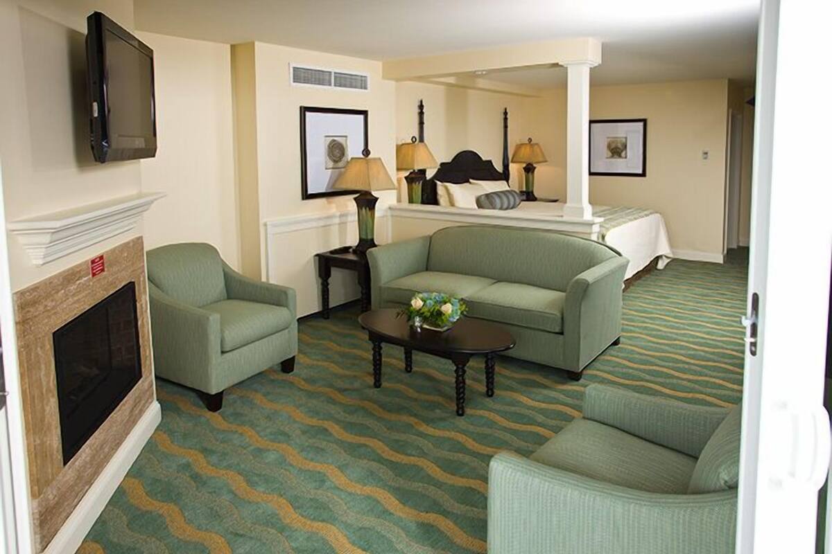 A hotel room with a fireplace, a sofa, a coffee table, and a bed with a canopy.