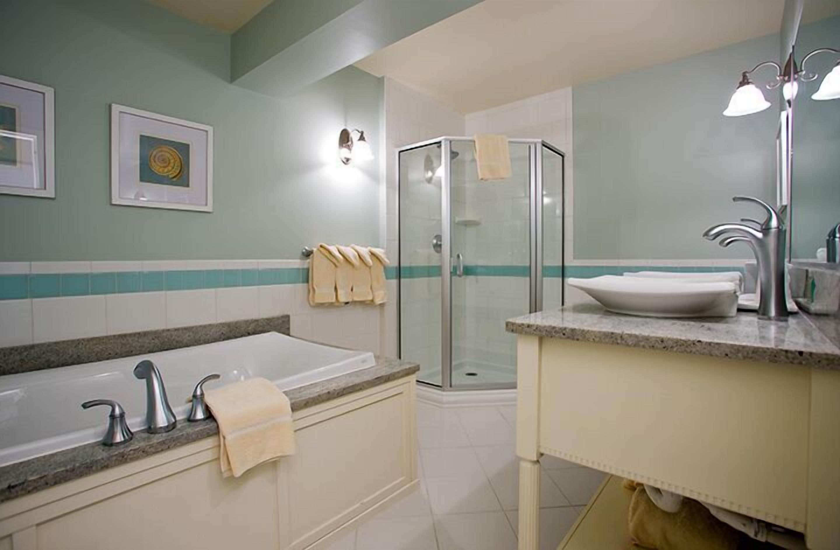 A bathroom with a bathtub, a glass shower enclosure, a sink with a mirror, and a towel rack.