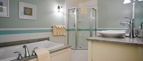 A bathroom with a bathtub, a glass shower enclosure, a sink with a mirror, and a towel rack.