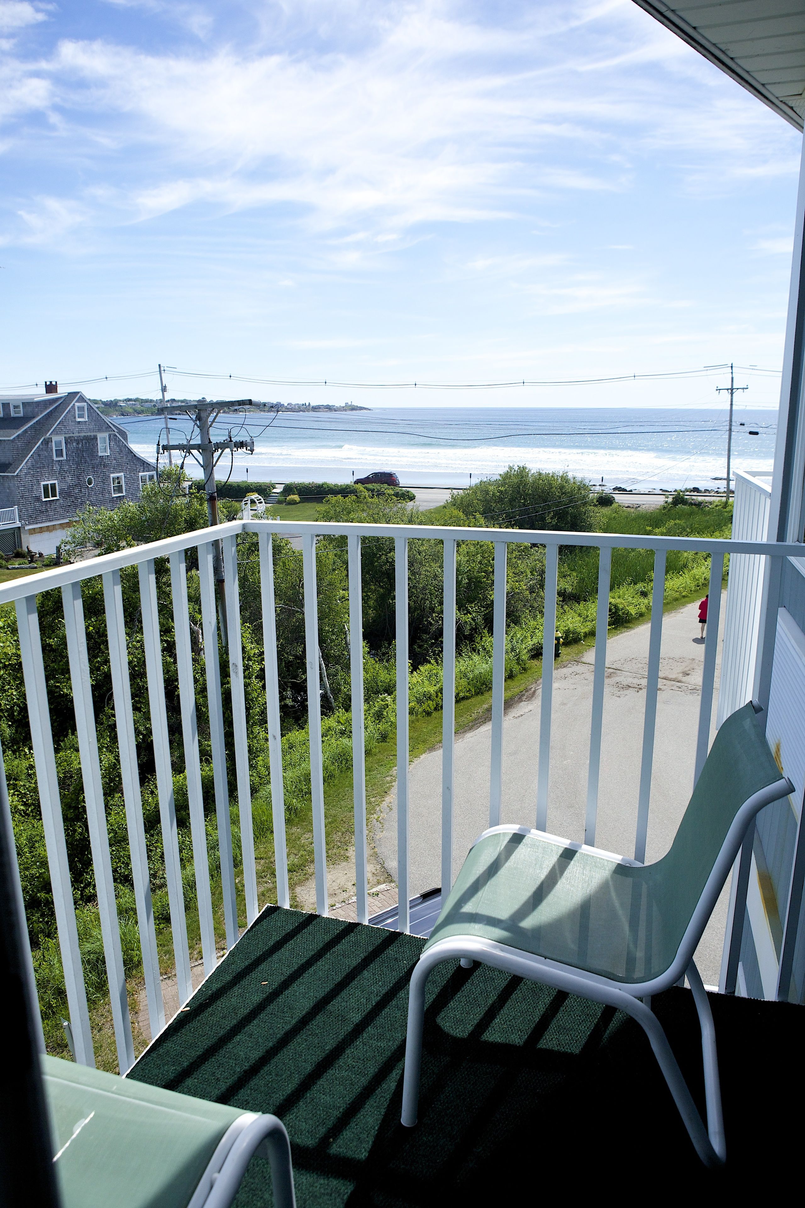 A balcony with a view of the ocean, a chair, and a small table.