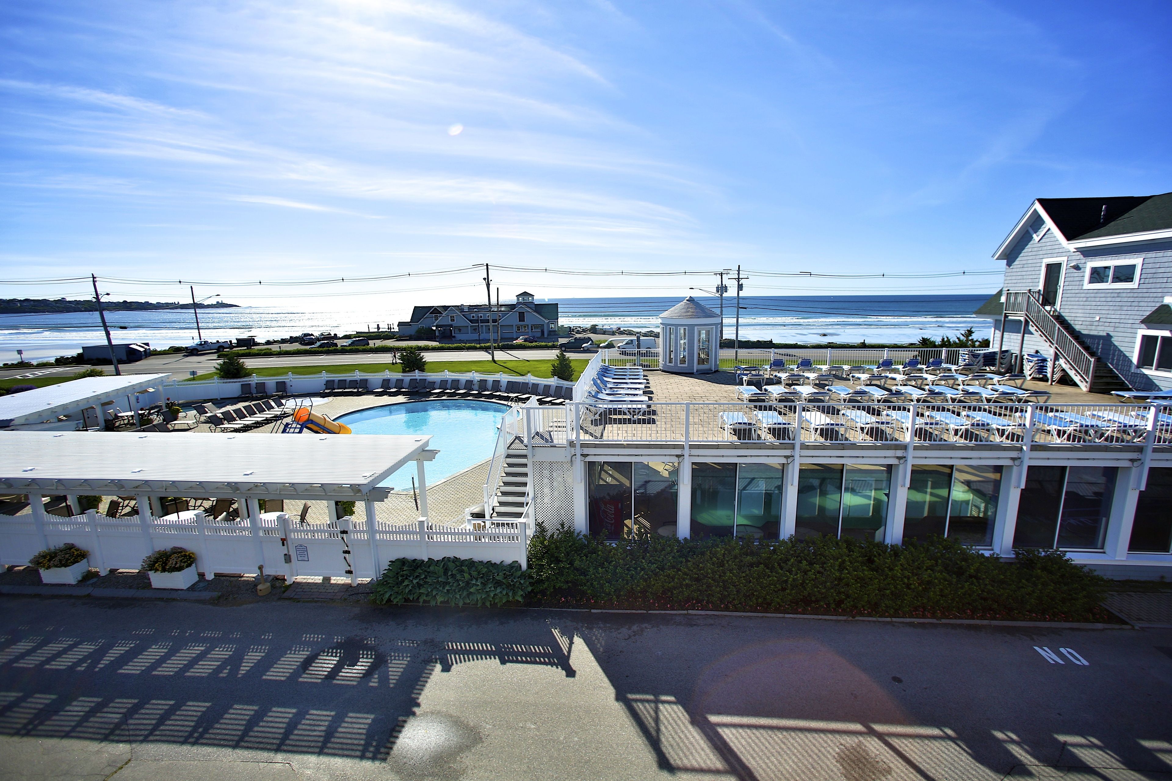 A hotel with a pool, outdoor seating, and a view of the ocean.