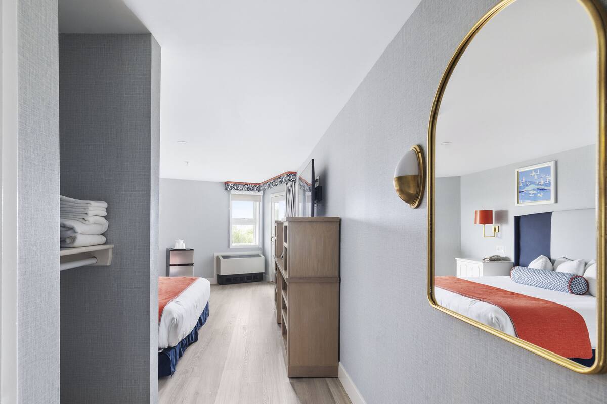 A hotel room with a bed, a wardrobe, a mirror, and a window.