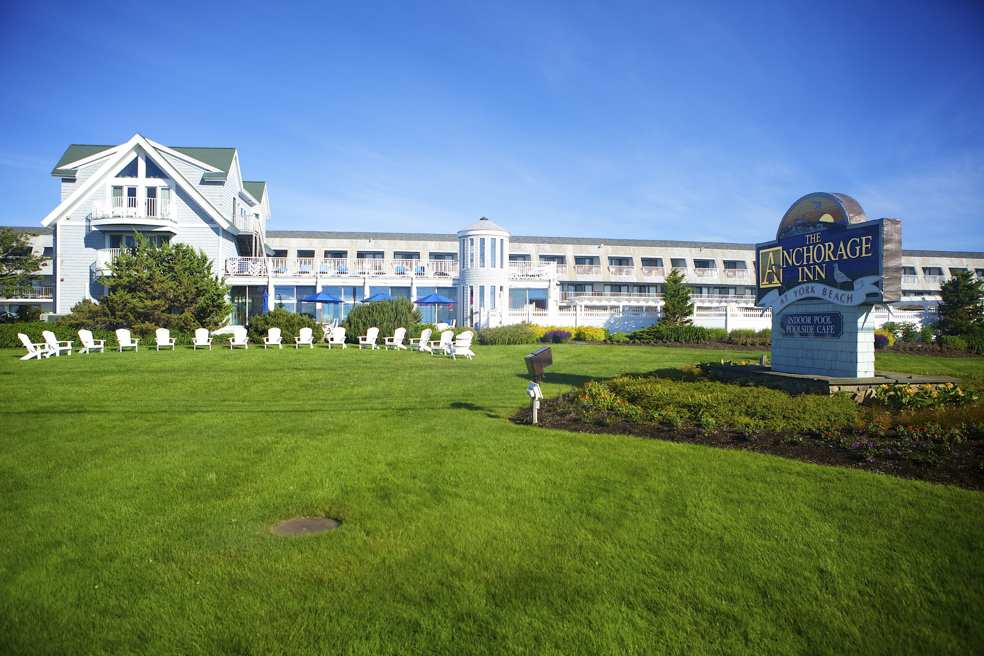 A hotel with a large lawn, outdoor seating area, and a sign for The Anchorage Inn.