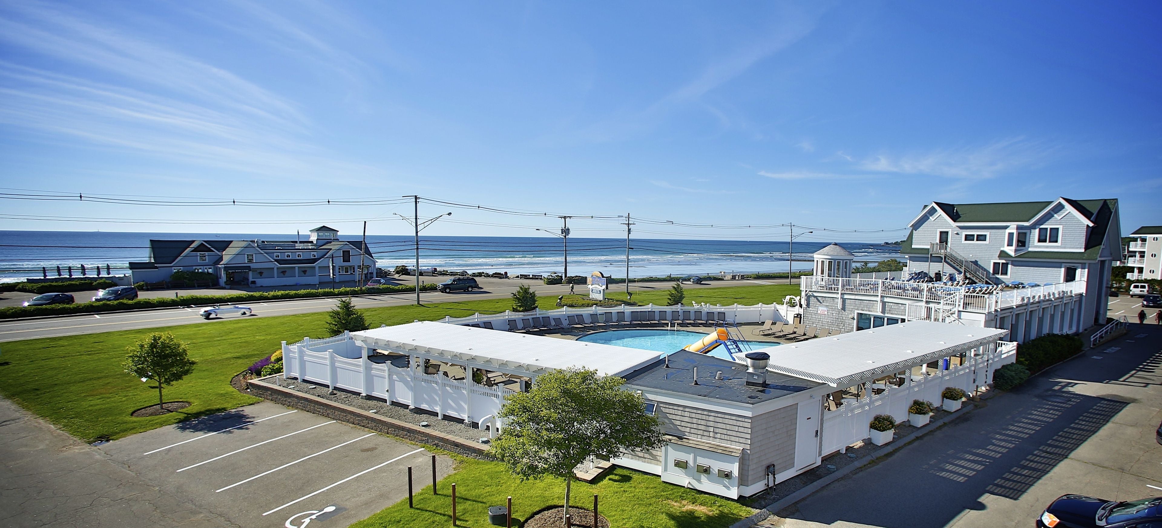 A large building with a swimming pool, a covered patio, and a view of the ocean.