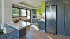 Uma cozinha moderna com uma ilha grande, eletrodomésticos de aço inoxidável e vista para o exterior.