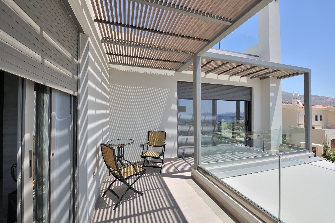 A modern balcony with glass railings, two wicker chairs, and a table.