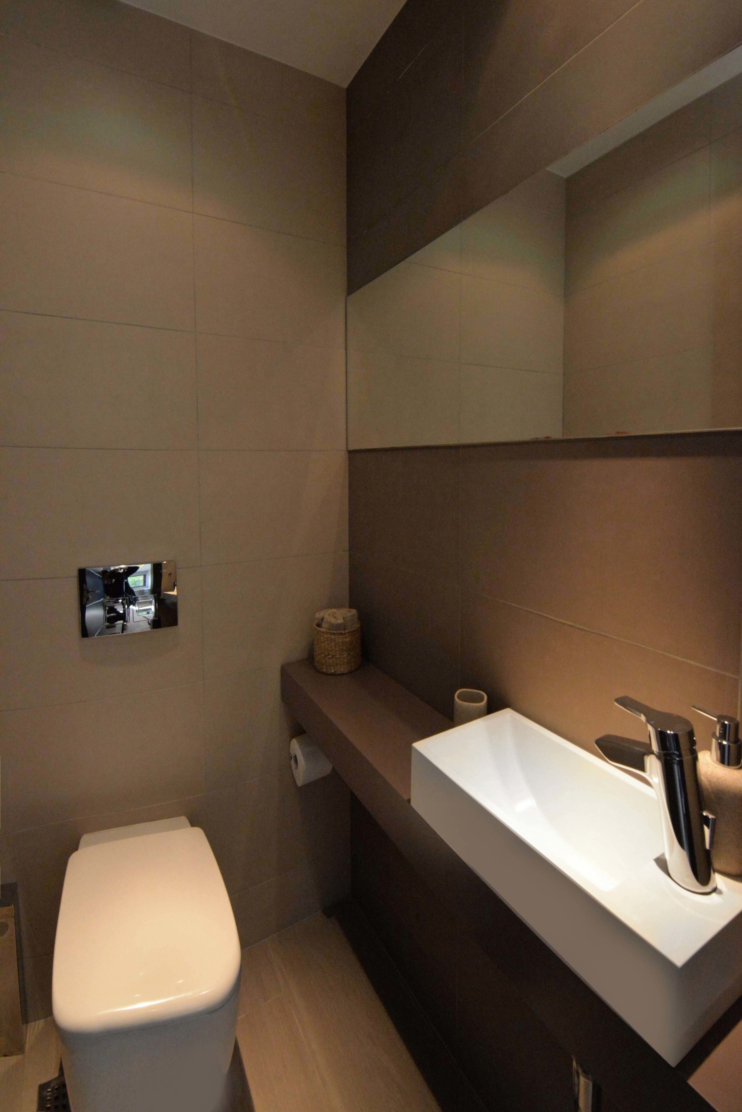 A modern bathroom with a toilet, a sink, and a mirror.