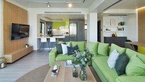 Uma sala de estar moderna com um sofá verde, uma mesa de centro e uma televisão de tela plana.