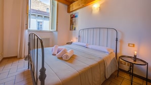 Un dormitorio con cama, mesita de noche, ventana y radiador.