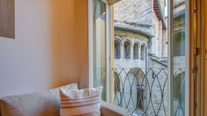 Habitación con sofá y ventana que da a un edificio de piedra con arcos.