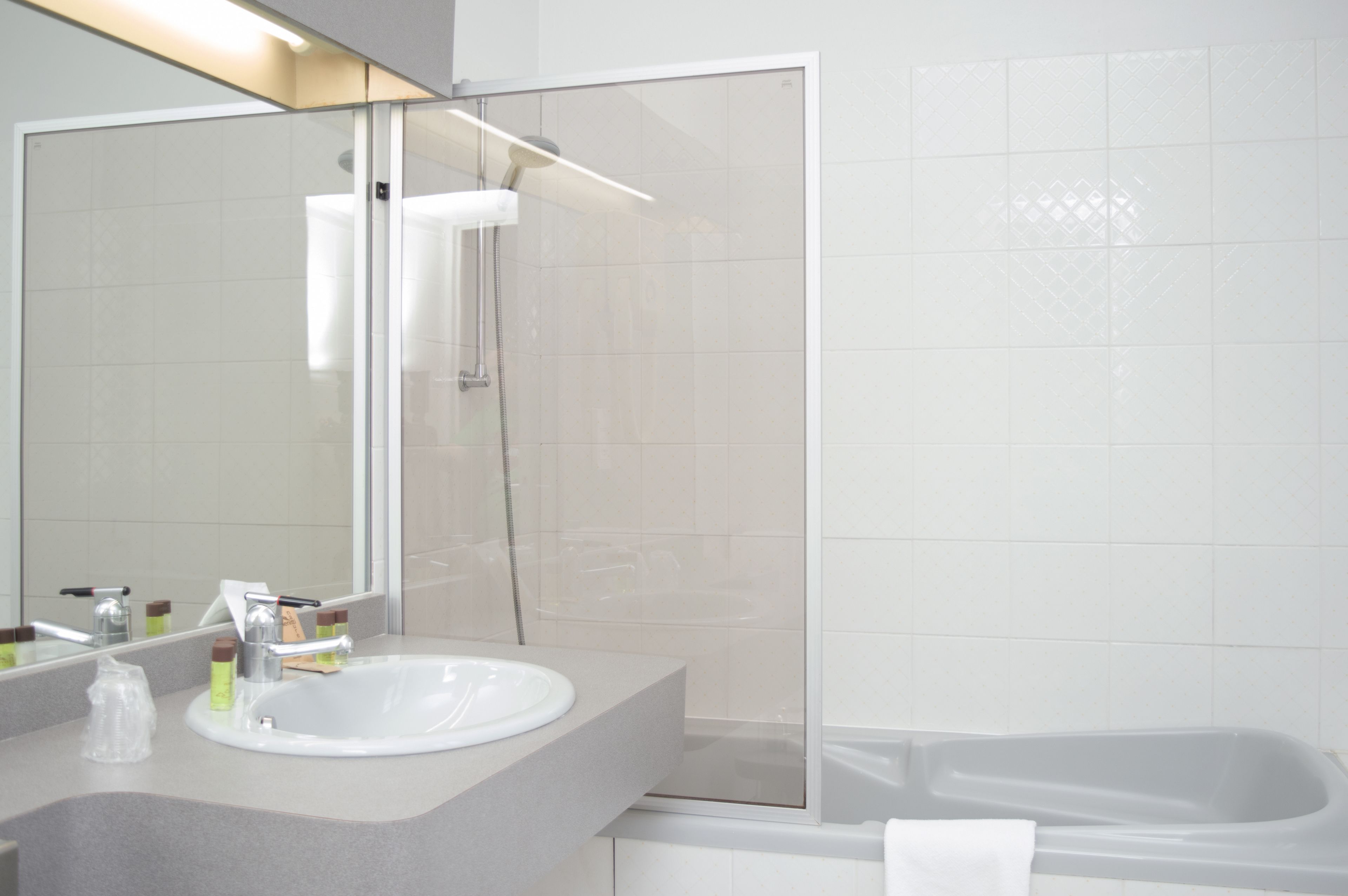 A modern bathroom with a glass-enclosed shower, a white sink, and a bathtub.
