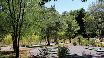 Un parque con diversos árboles, un sendero de grava y un pequeño estanque.