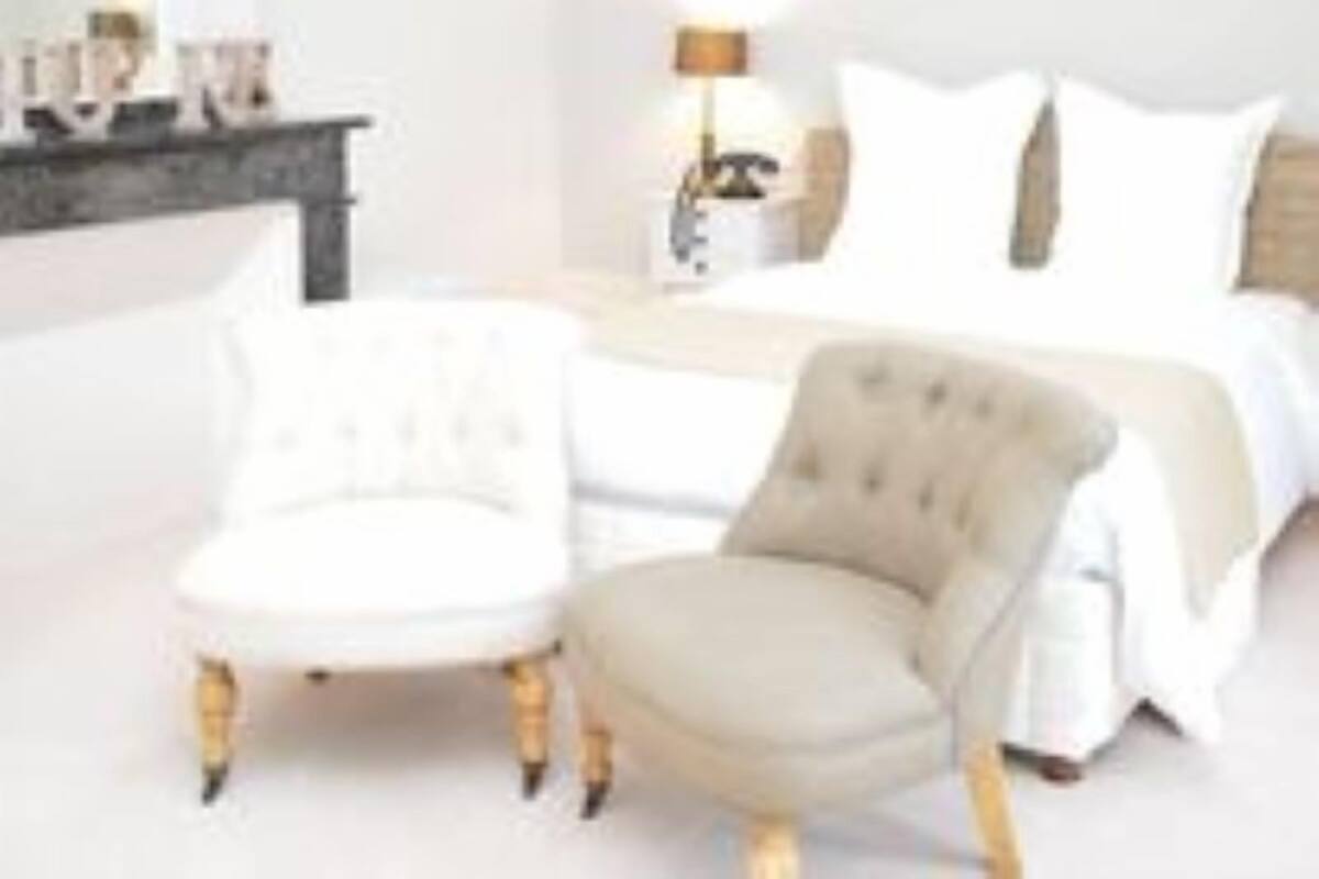 A bedroom with a bed, bedside table, lamp, and a chair.