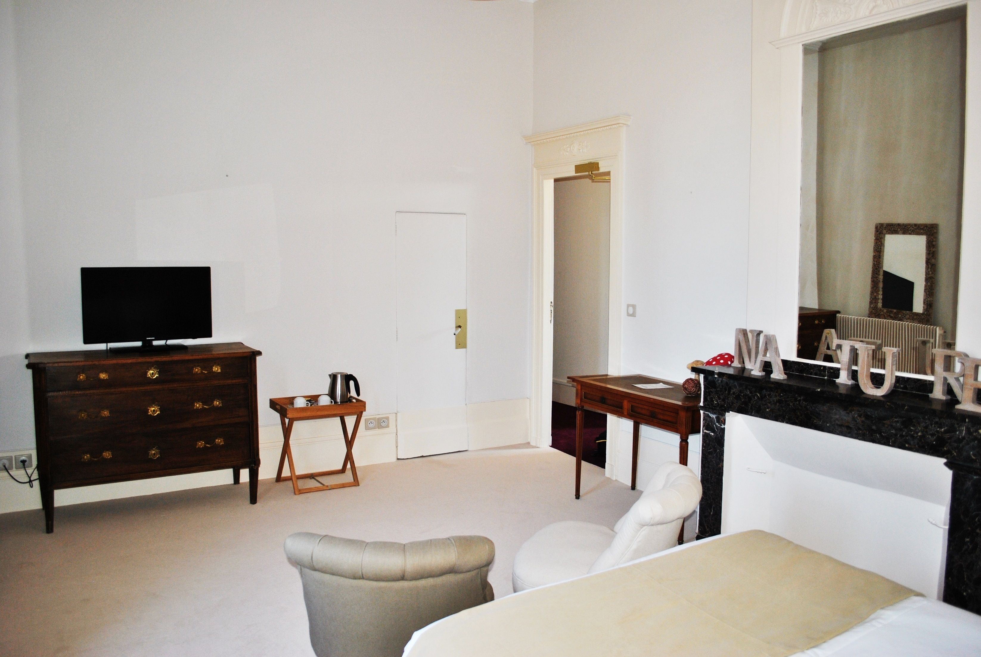 A hotel room with a bed, a dresser, a television, a small table, and a mirror.