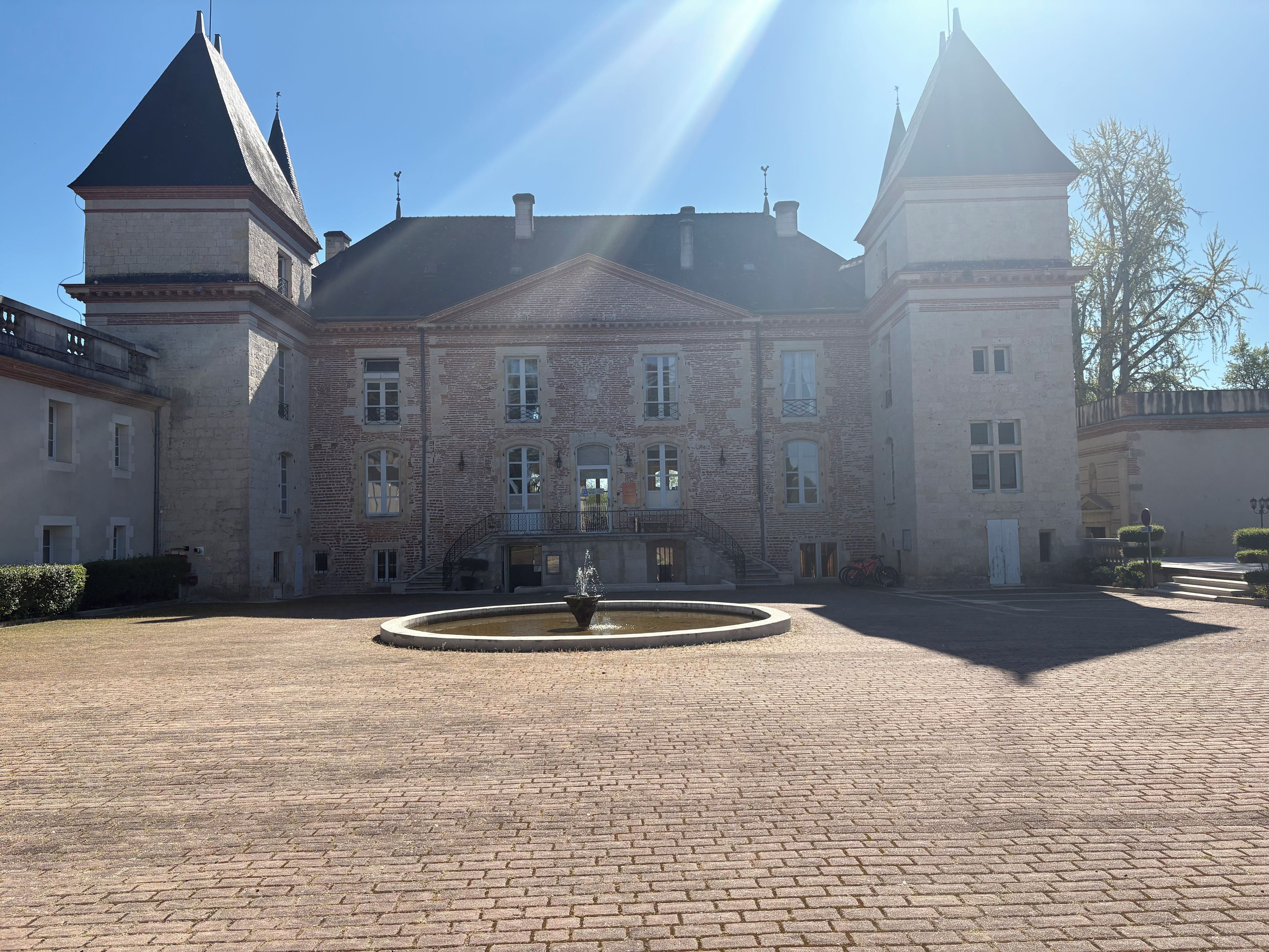A historic building with a courtyard, a fountain, and a clear sky.