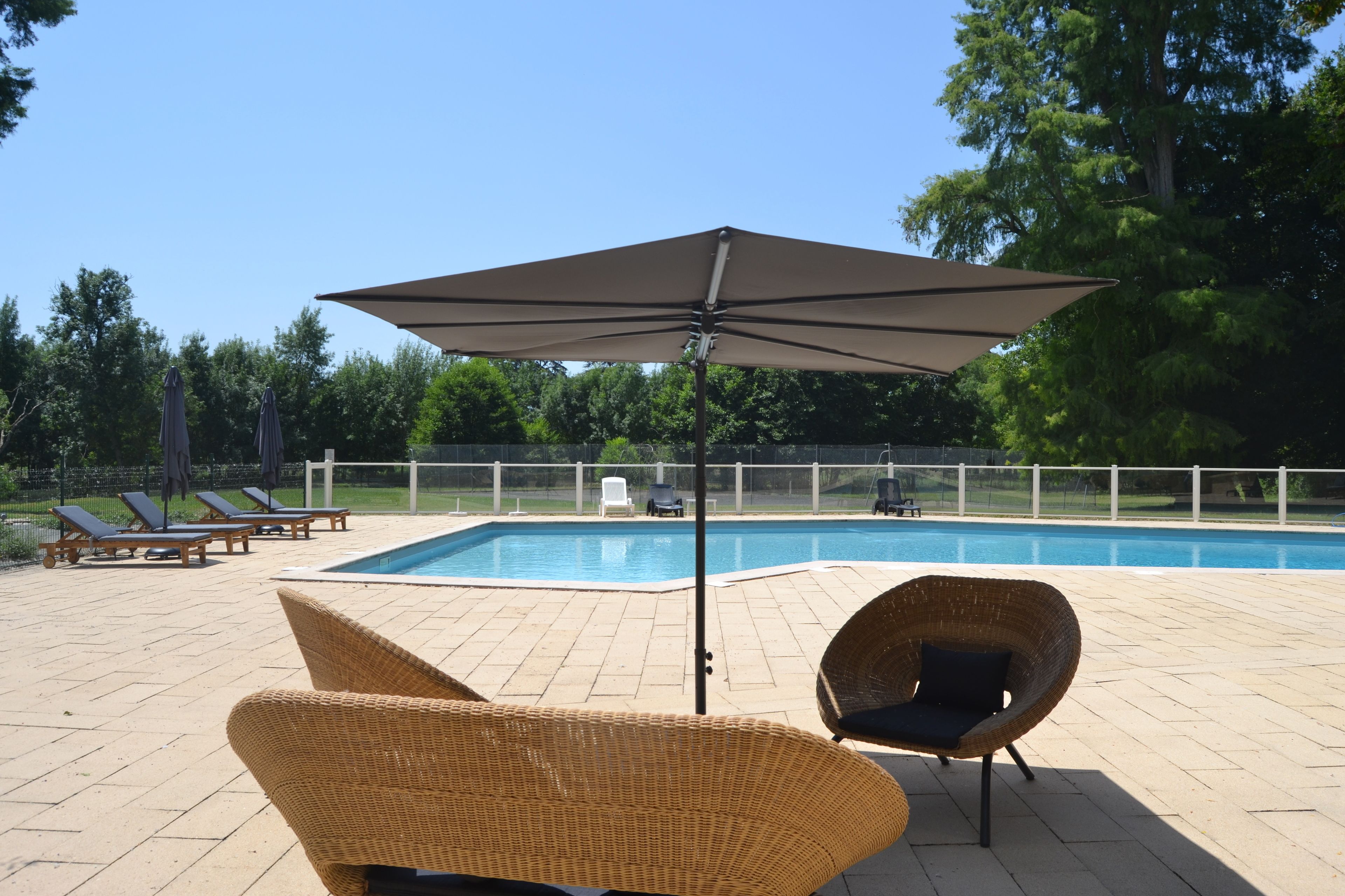 A poolside area with lounge chairs, a large umbrella, and a swimming pool.