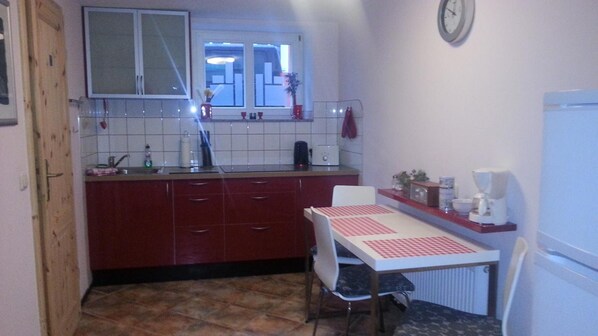 A compact kitchen with a tiled backsplash, a window above the sink, and a clock on the wall.