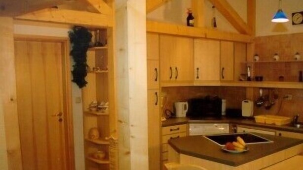 Eine Küche mit Holzschränken, einer Mikrowelle und einem Spülbecken.