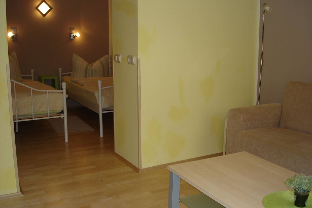 A room with a bed, a chair, a table, and a lamp.