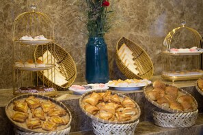 Un buffet con dolci e pasticcini di vario tipo esposti in cesti e su piatti.