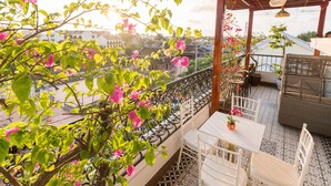 A balcony with a tiled floor, white chairs, a table, and a hanging light fixture. - Hoang Trinh Hotel (Da Nang)