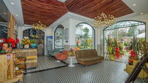 A lobby with a patterned floor, a reception desk, a sofa, and a staircase. - Hoang Trinh Hotel (Da Nang)