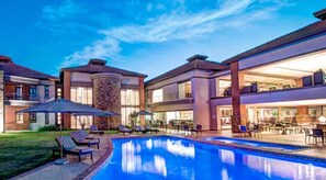 Un hotel moderno con piscina, zona de estar al aire libre y un patio bien iluminado.