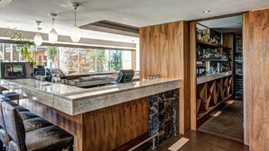Un área de bar moderna con encimera de granito, detalles de madera y una estantería para vinos.